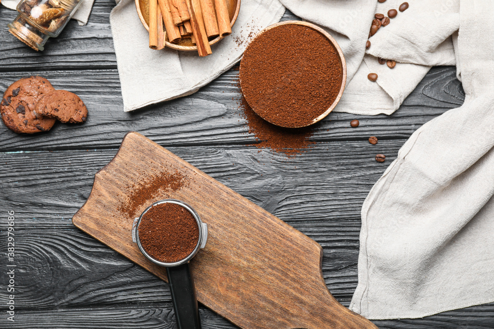 Portafilter with coffee powder, spices and cookies on dark wooden background