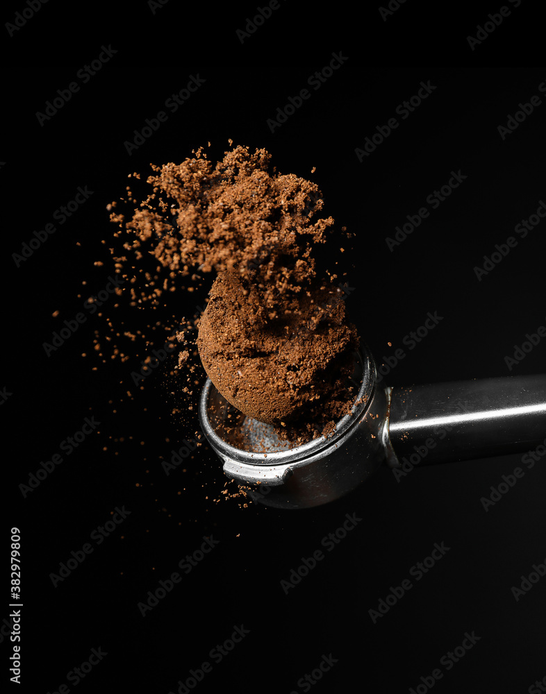 Portafilter with coffee powder on dark background