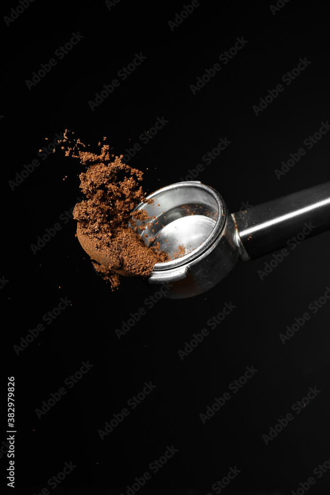 Portafilter with coffee powder on dark background