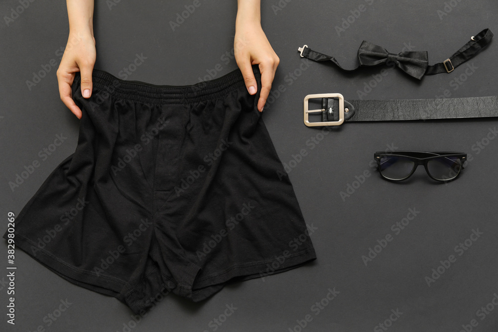 Female hands with stylish male underwear and accessories on dark background