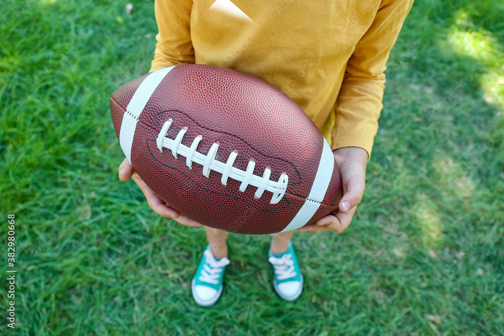 Little boy playing American football outdoors