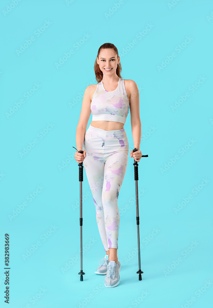 Young woman with walking poles on color background