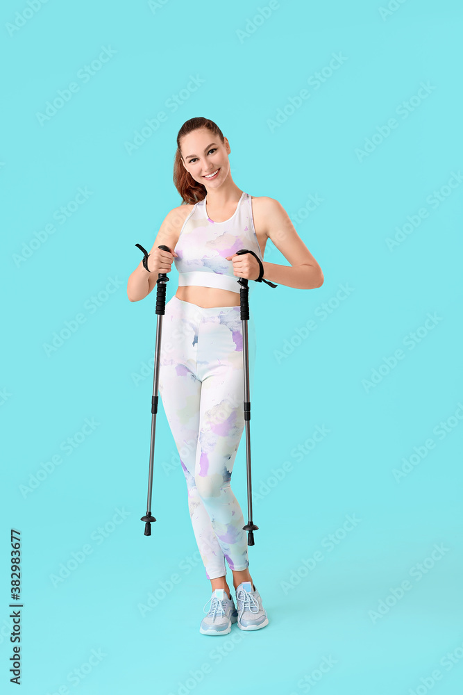 Young woman with walking poles on color background