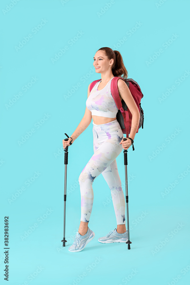 Young woman with walking poles on color background