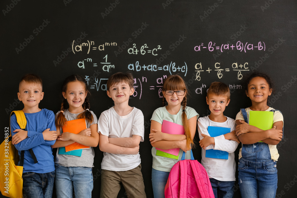 Cute pupils near blackboard in classroom