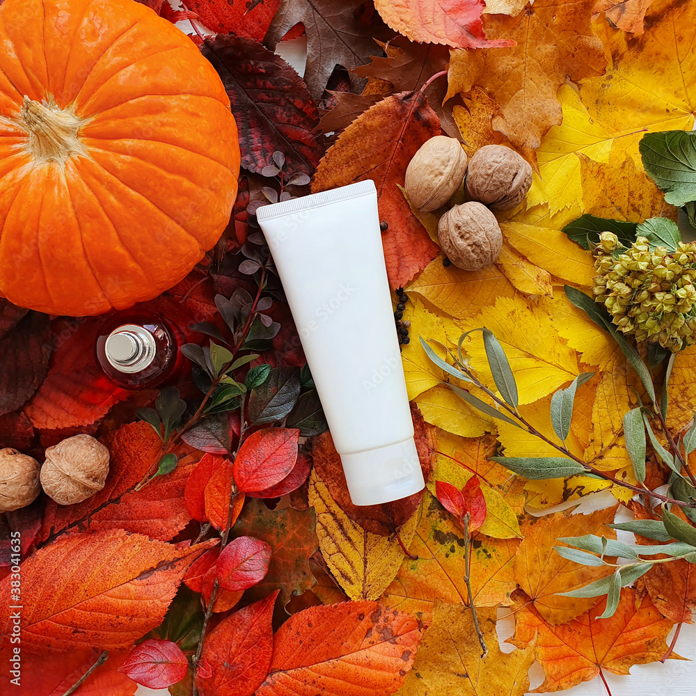 Mockup of white squeeze bottle plastic tube, pumpkin, magic lights and bright autumn leaves. Atmosph