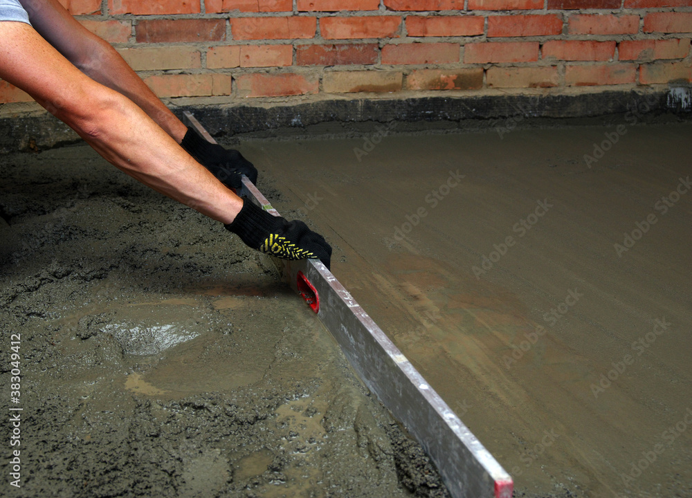 worker screeding indoor cement floor with screed