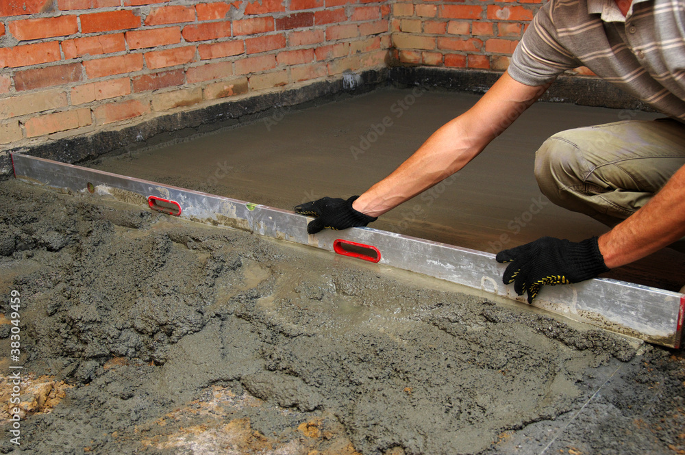 worker screeding indoor cement floor with screed