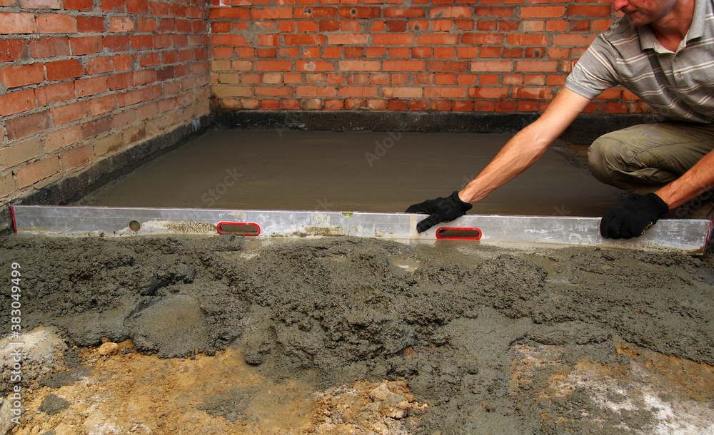 worker screeding indoor cement floor with screed