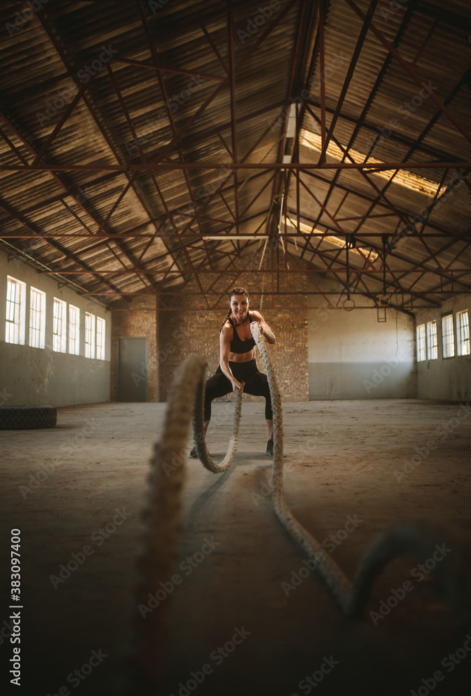 Tough female working out with battling ropes