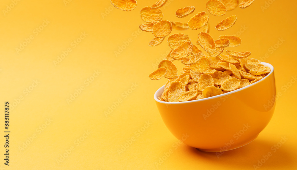 Ceramic bowl with falling corn flakes on yellow background