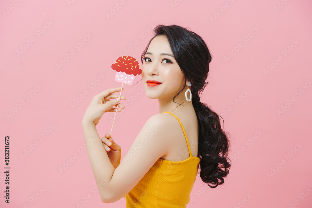 Woman holding fake paper cupcake, muffin sticks on festive background.