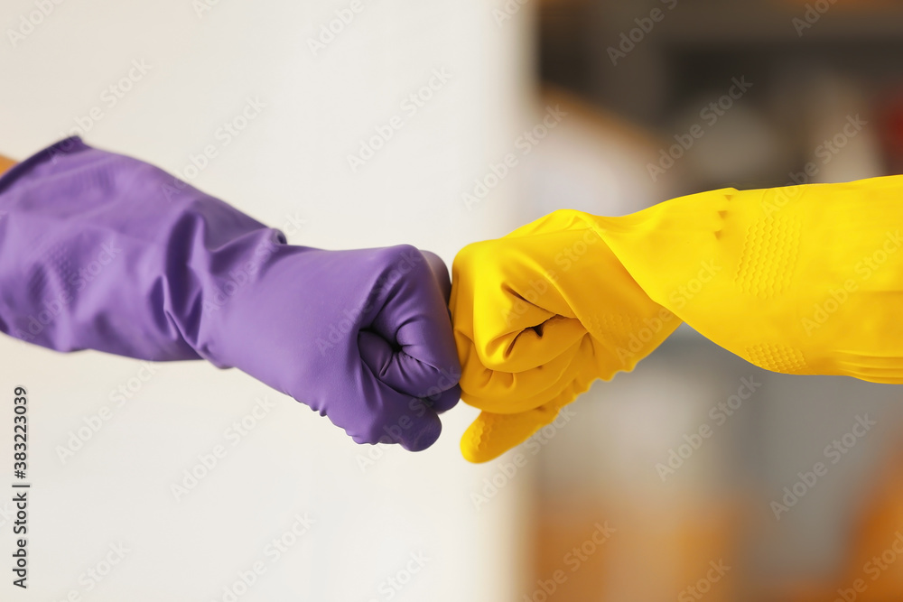 Women in rubber gloves bumping fists at home