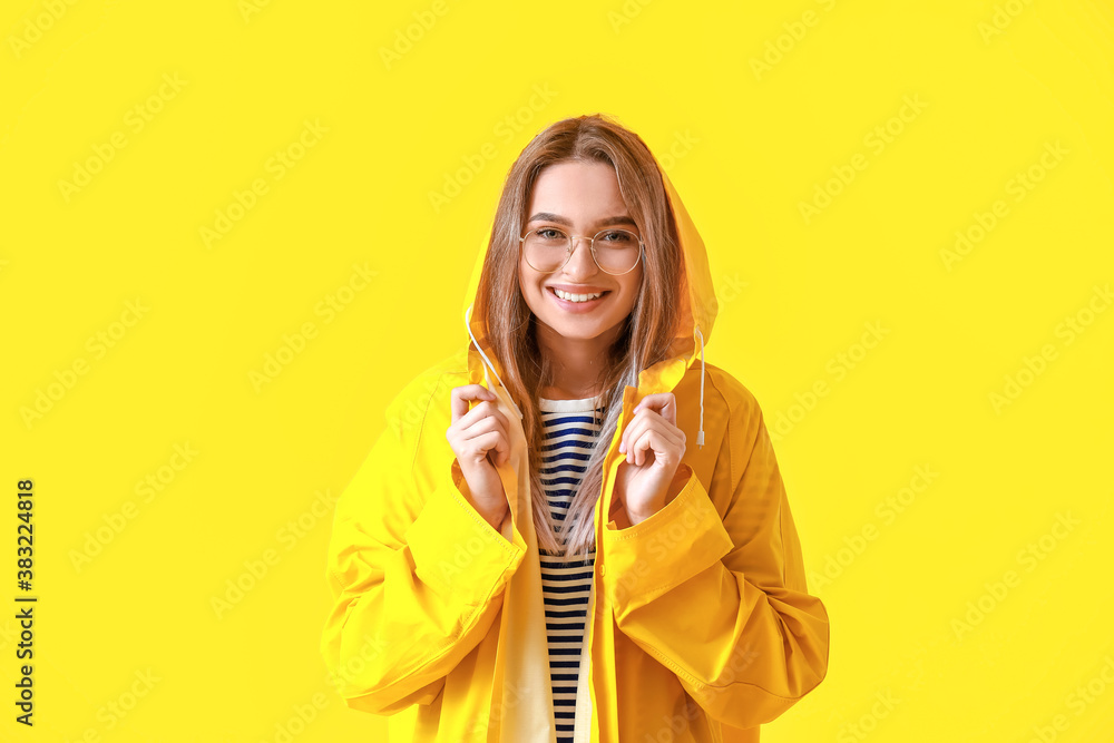 Beautiful young woman in raincoat on color background