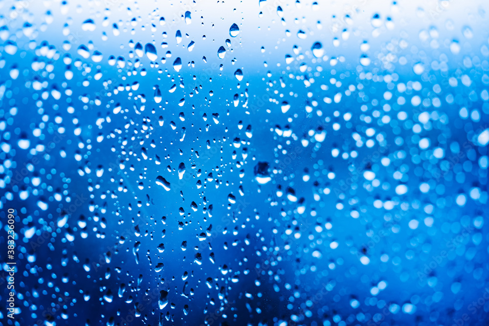 Droplets of water on enlighted glass background. Rain water drops running down. Water droplets falli