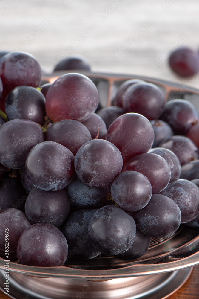 Delicious bunch of grapes fruit on a plate over wooden table background.