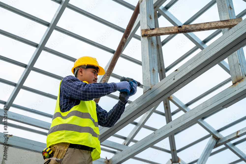 Construction worker using electric drill on house build.