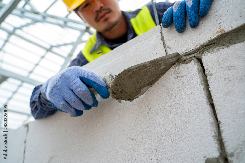 Construction worker plastering cement at wall for building house.