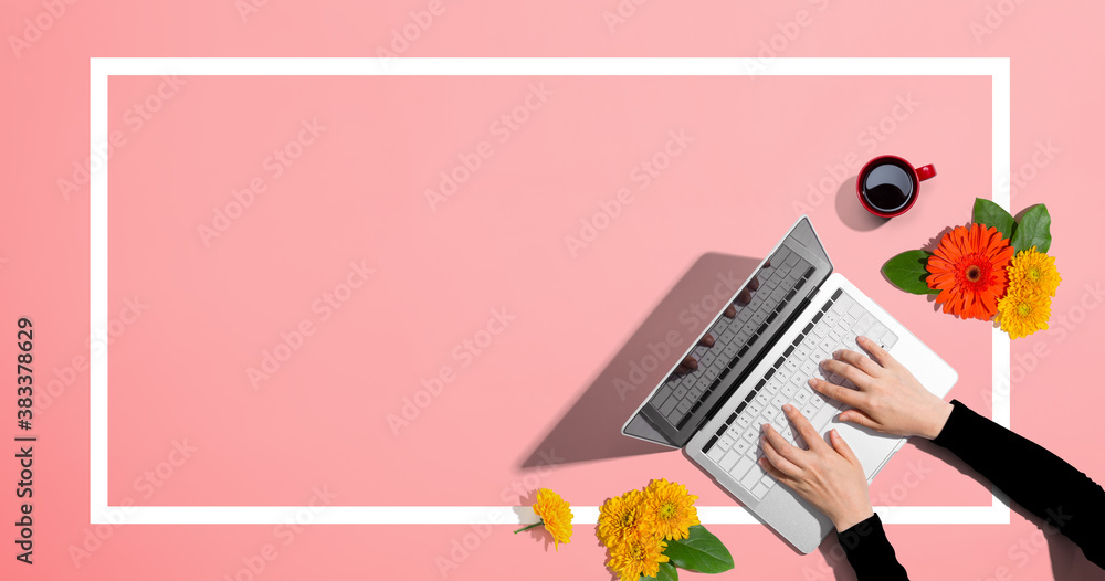 Person using a laptop computer with autumn flowers - overhead view