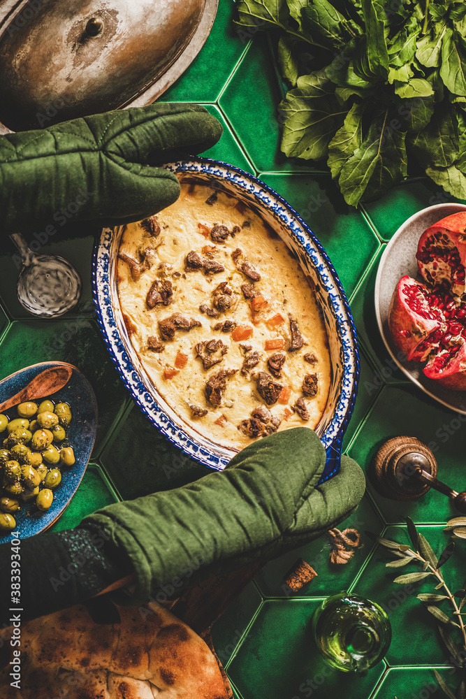 Turkish style family dinner concept. Flat-lay of cooks hands in gloves putting stewed lamb in yogurt