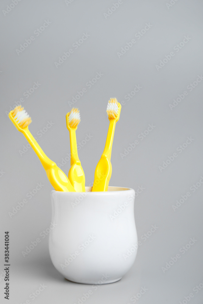 Cup with tooth brushes on grey background