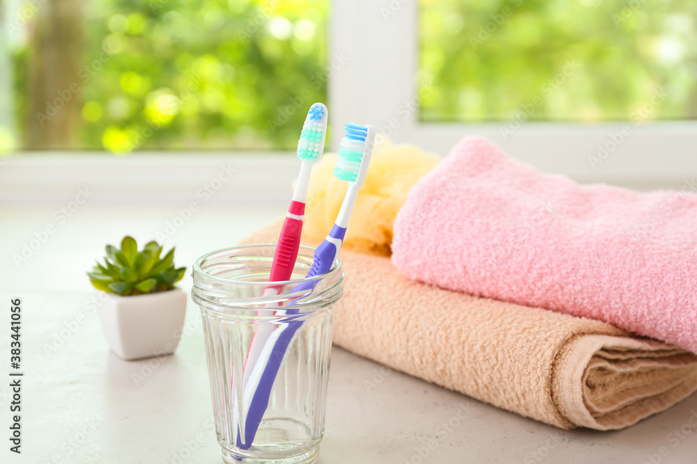 Tooth brushes and towels on table in bathroom