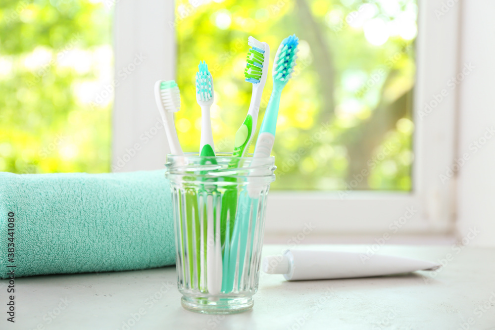 Cup with tooth brushes on table in bathroom