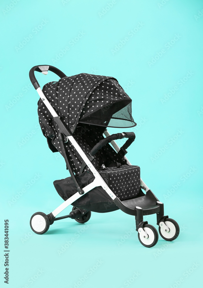 Modern baby stroller on color background