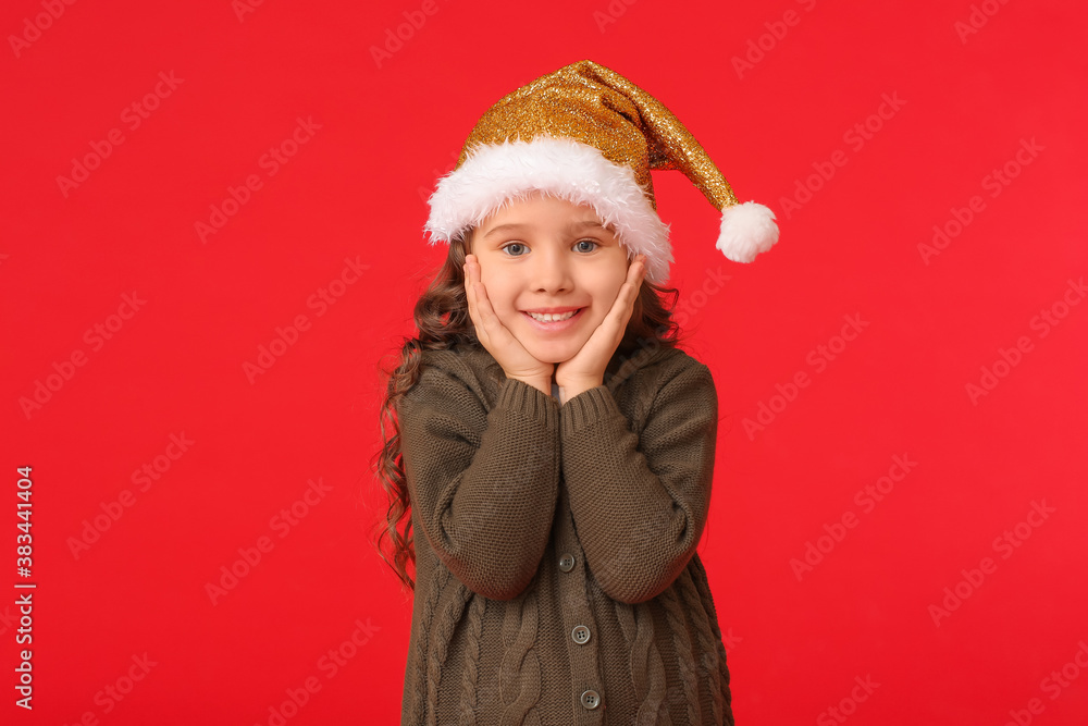 Cute little girl in Santa hat on color background