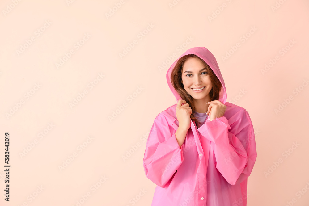 Beautiful young woman in raincoat on color background