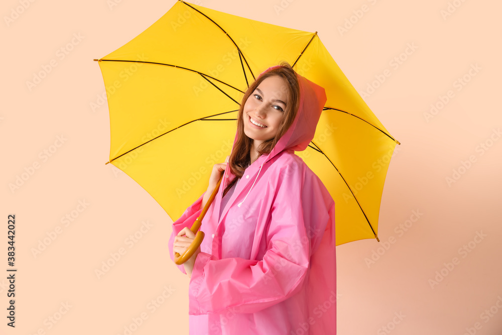 Beautiful young woman in raincoat and with umbrella on color background