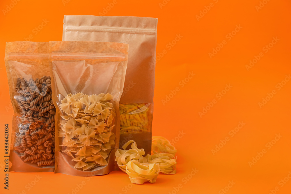 Bags with different pasta on color background