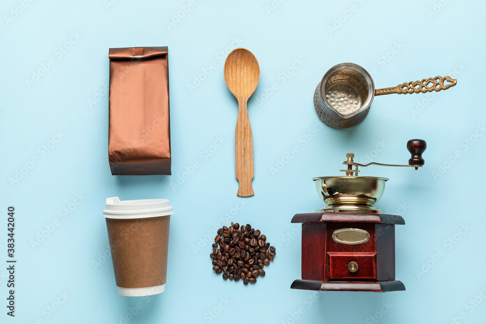 Paper bag with coffee grinder, cup, pot, spoon and beans on color background