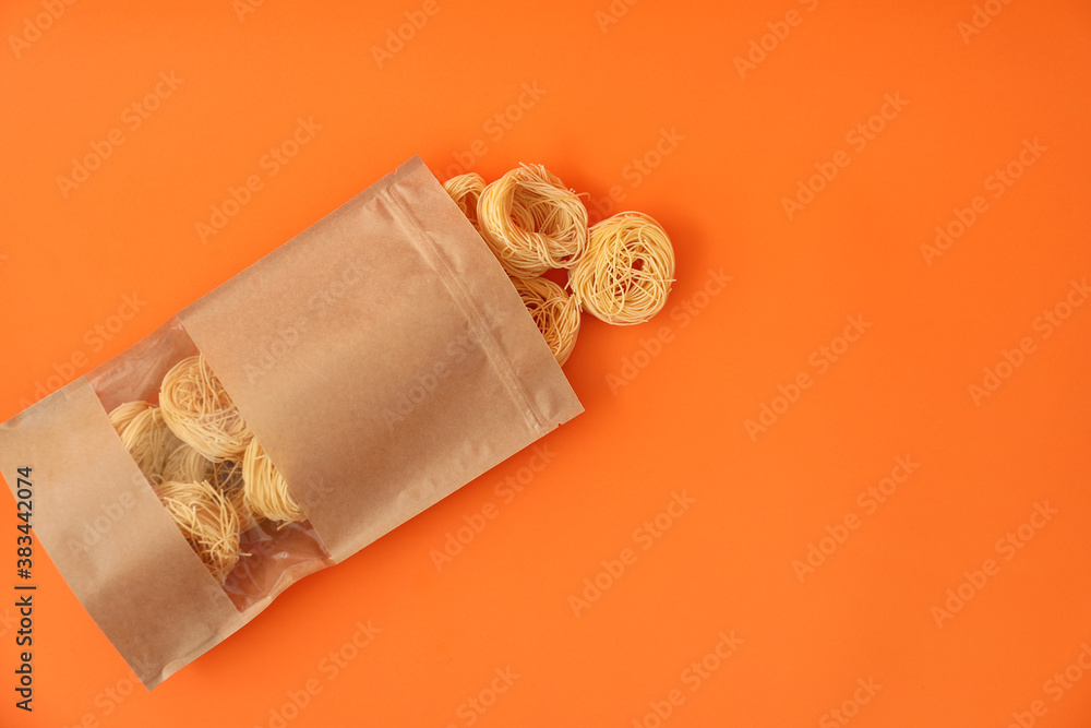 Paper bag with pasta on color background