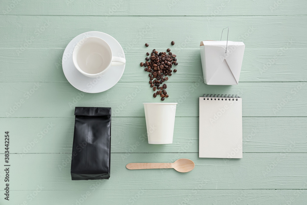 Paper packages with cup and coffee beans on wooden background