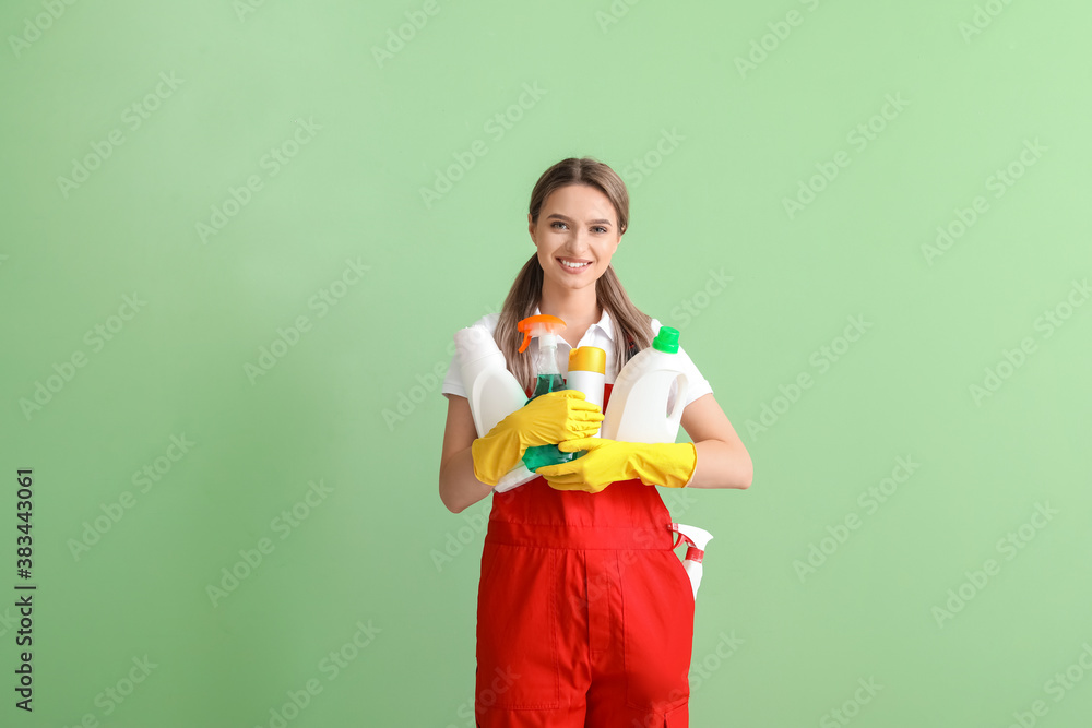 Young woman with cleaning supplies on color background