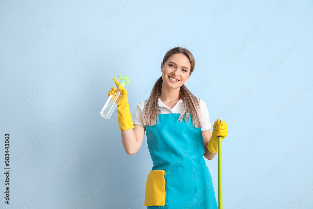 Young woman with cleaning supplies on color background