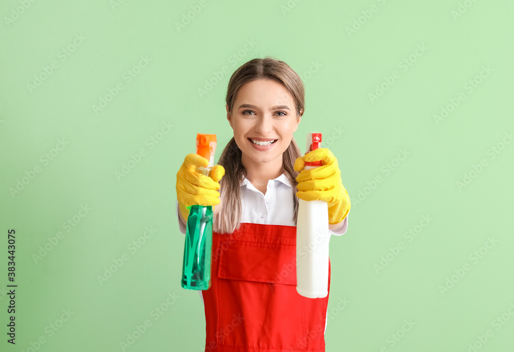 Young woman with cleaning supplies on color background