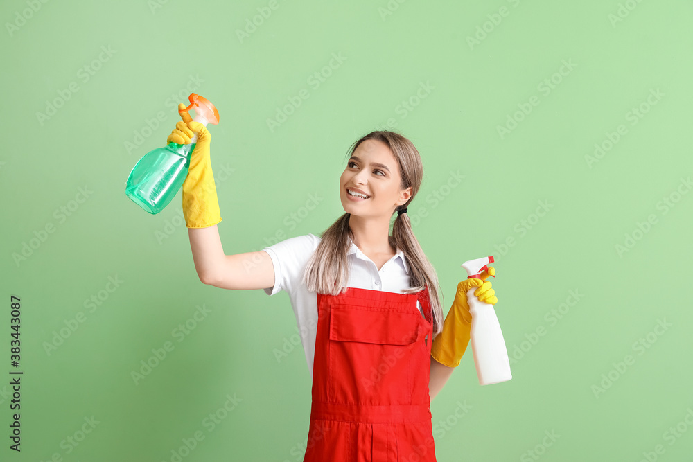 Young woman with cleaning supplies on color background