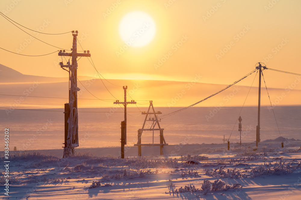 Electric poles in the snow-covered tundra in the Arctic. Winter landscape. View of electric poles an