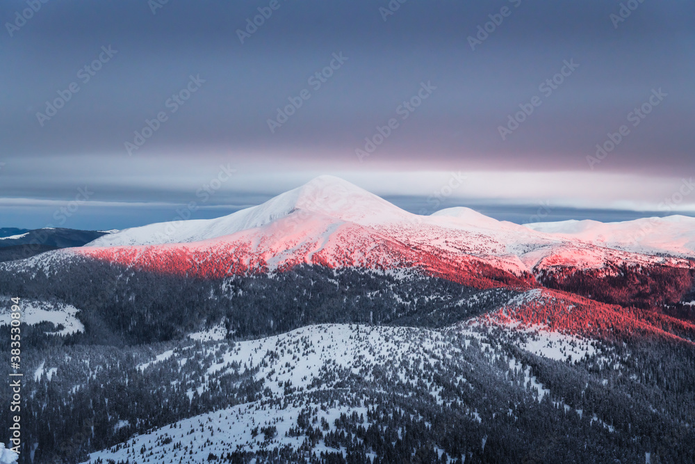 Fantastic orange winter landscape in snowy mountains glowing by sunlight. Dramatic wintry scene with