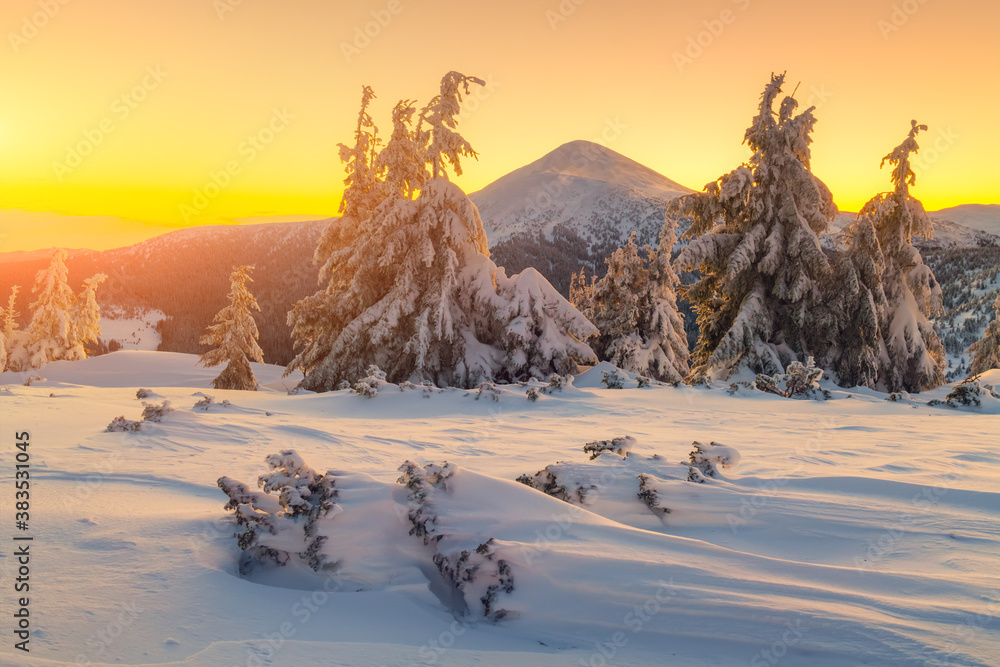 Fantastic orange winter landscape in snowy mountains glowing by sunlight. Dramatic wintry scene with