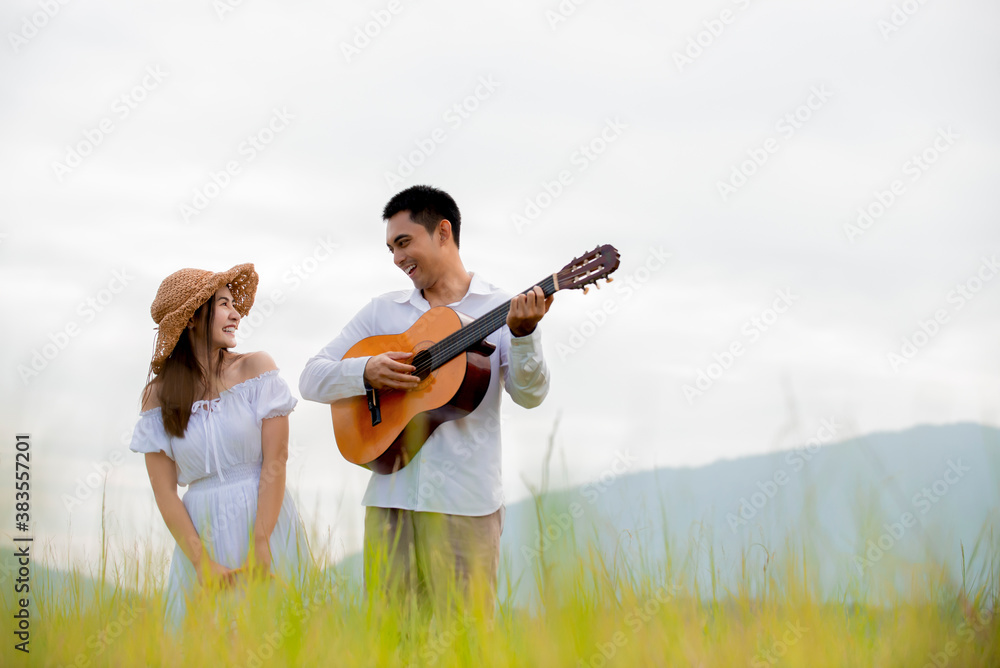 Happy asian couple playing  guitar in picnic day at park