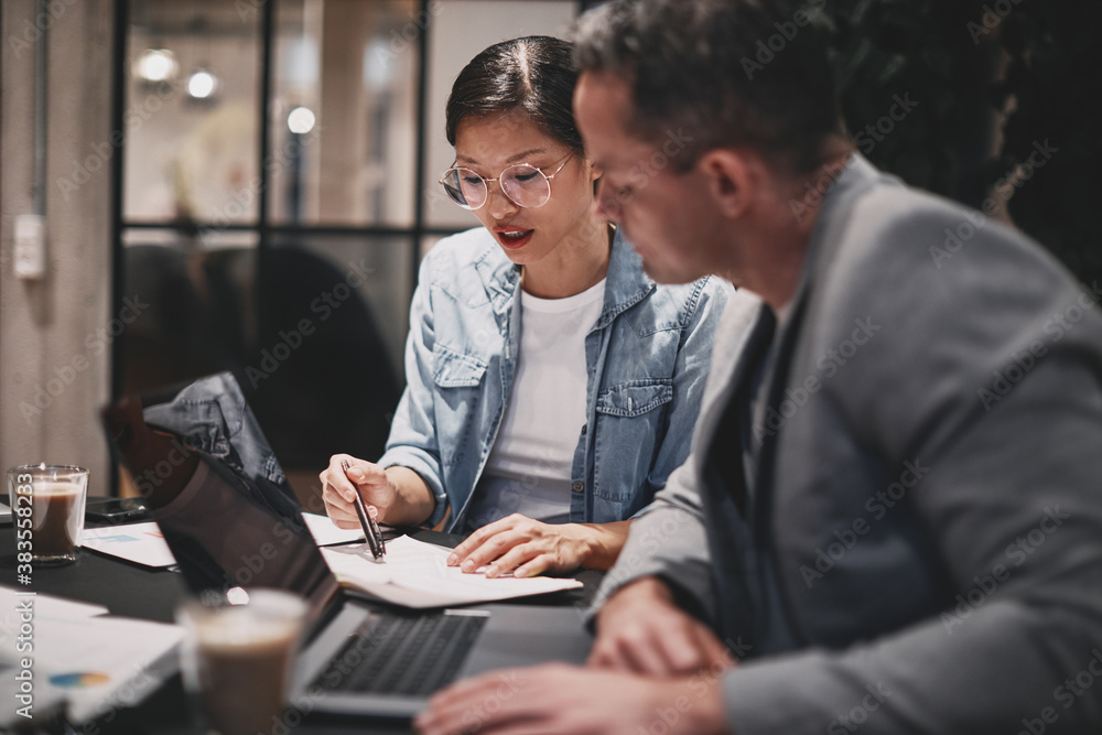 Two businesspeople sitting at a table and going over paperwork