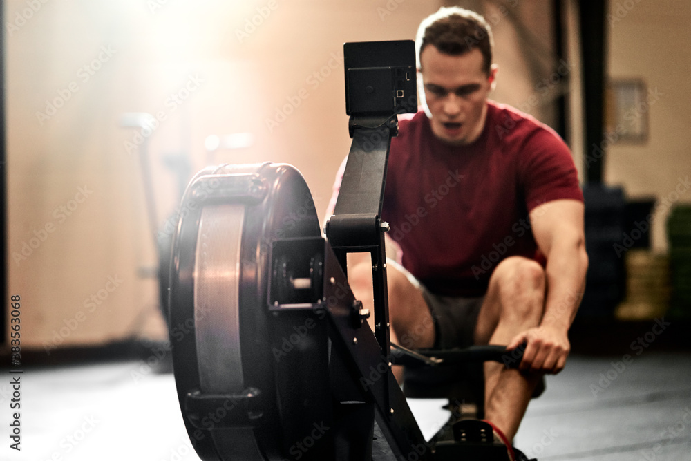 Young man doing a rowing machine workout in a gym