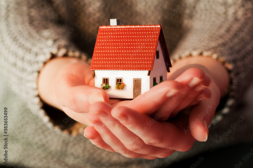 Woman holding a small new house in her hands. Real estate, mortgage