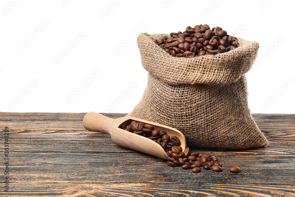 Bag with coffee beans on table against white background