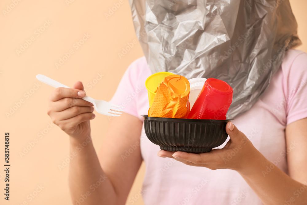 Woman with plastic tableware on color background. Ecology concept