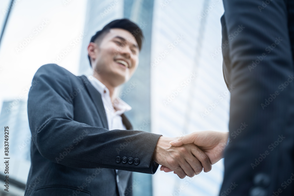 Asian businessmen make handshake in the city with building background.