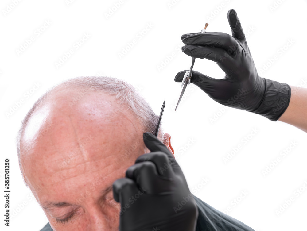 Closeup image of senior man in barber shop.Barber cutting hair with scissors over white background